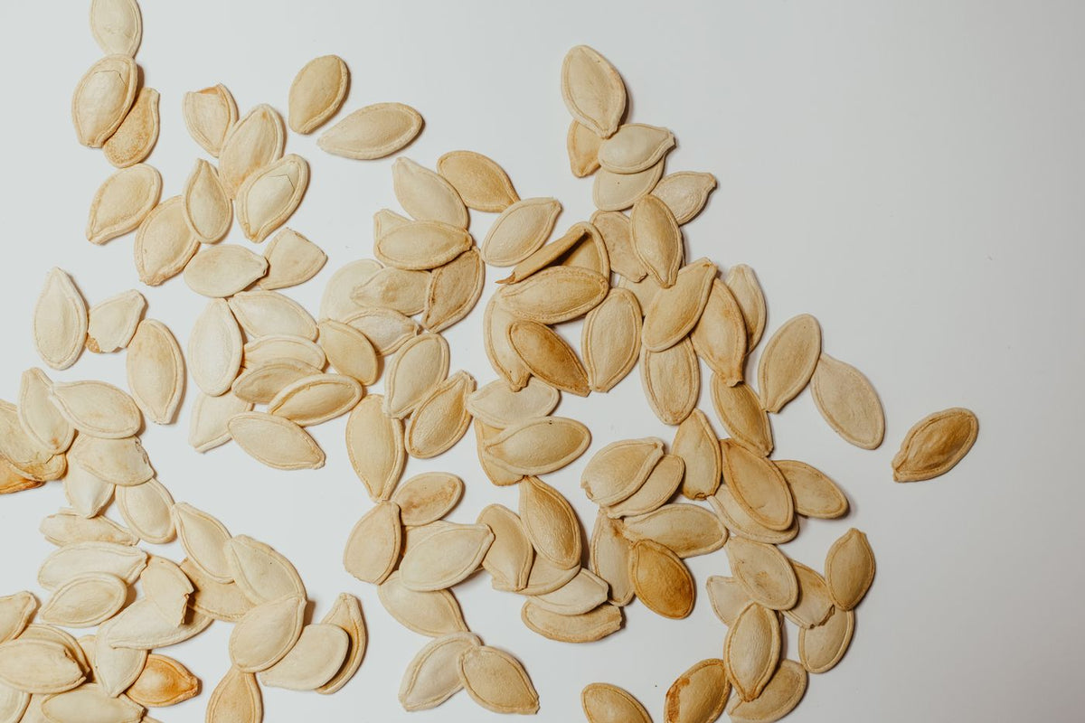 Raw pumpkin seeds scattered on a white surface