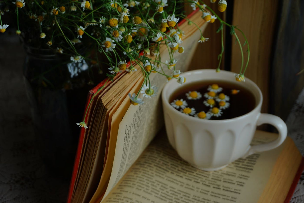 A cup of chamomile tea beside an open book