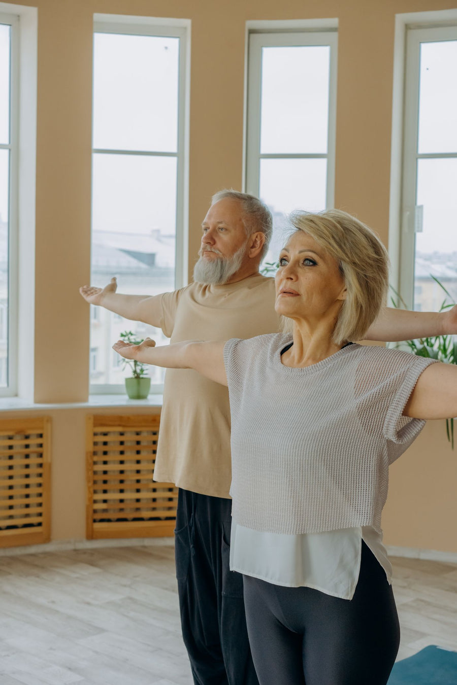 An older couple doing yoga stretches