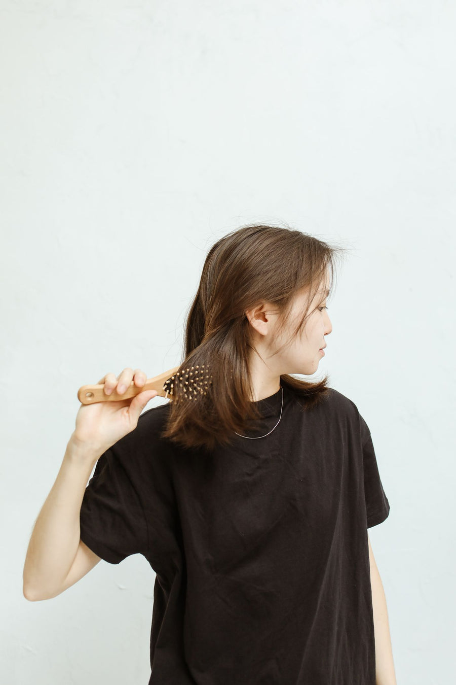 A woman combing her hair with a wooden brush