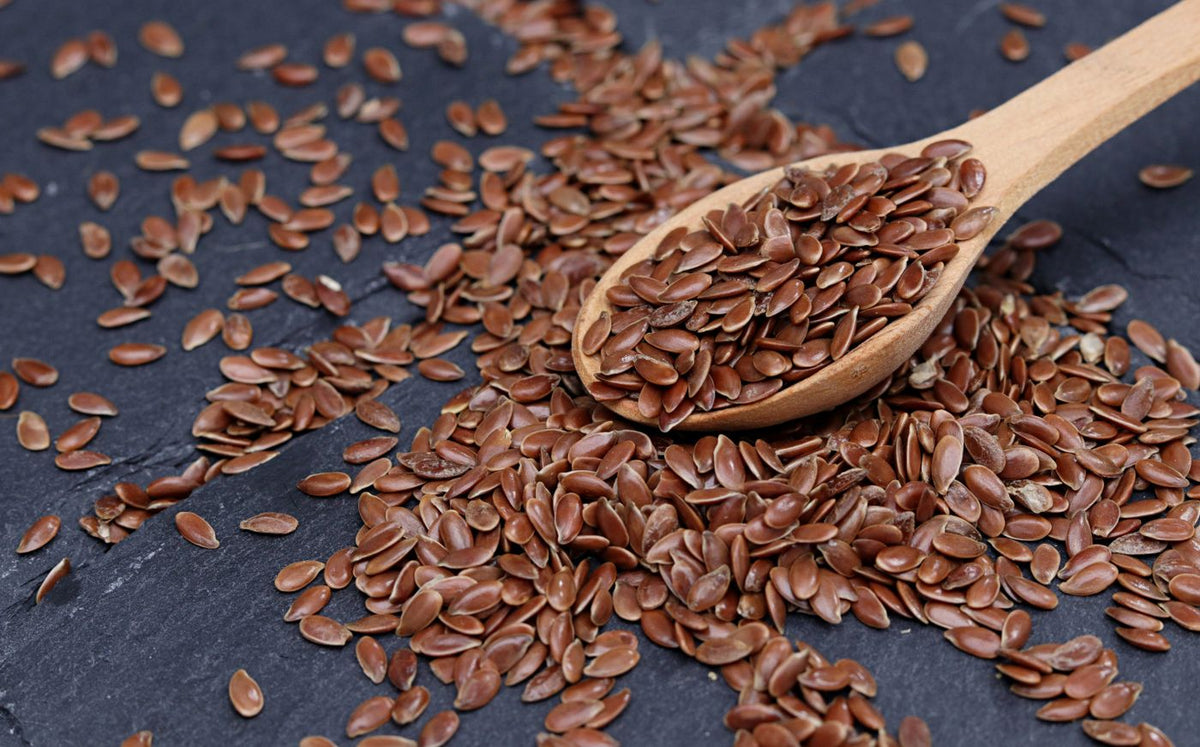 Flax seeds with a wooden spoon on slate