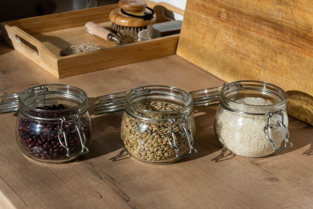 Glass jars of beans, lentils and uncooked rice on a wooden table