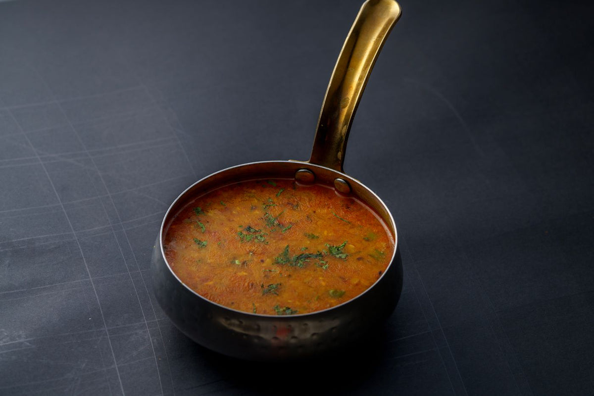 Indian dal garnished with herbs in a copper pot