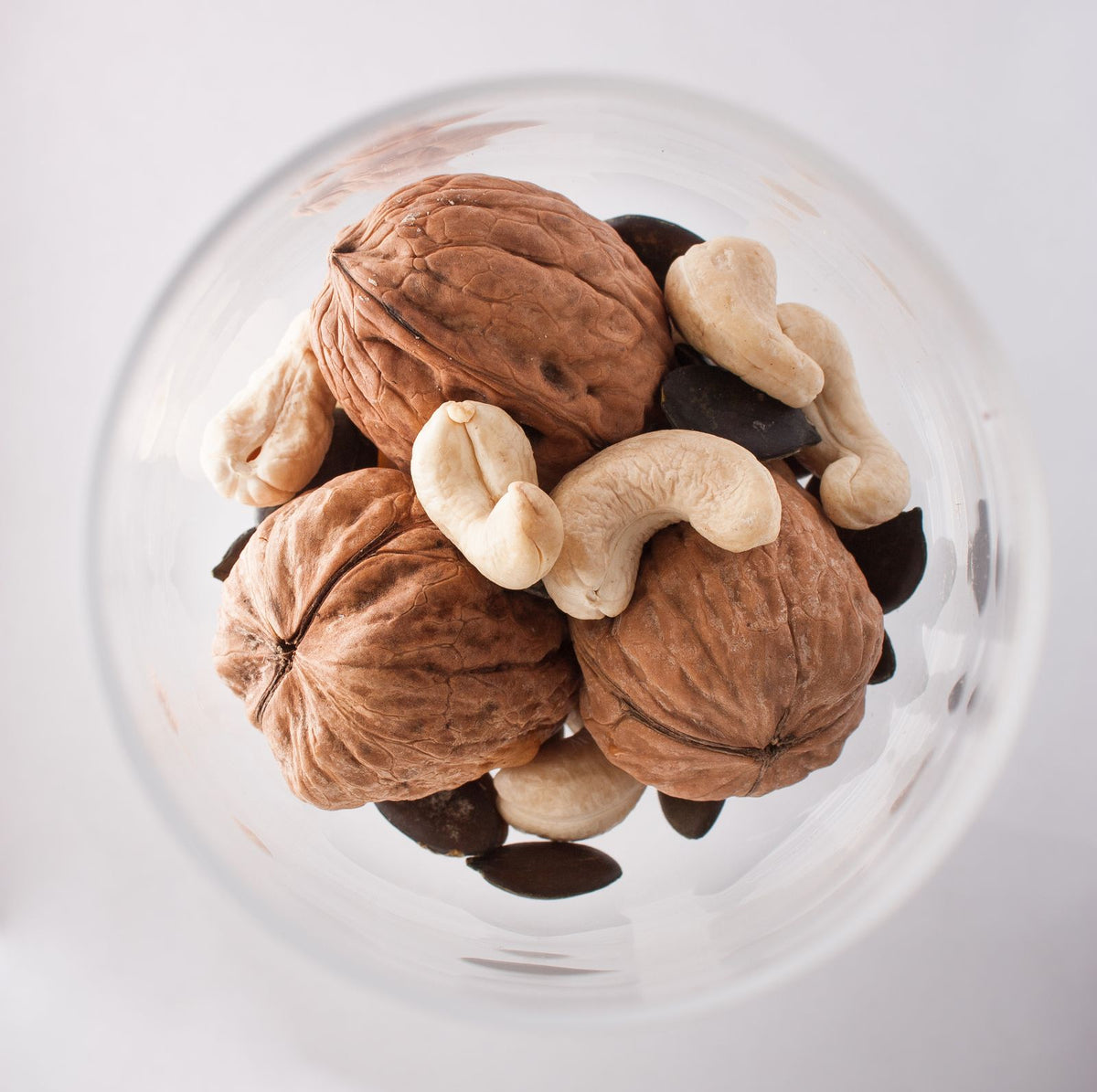 Walnuts, cashews and pumpkin seeds in a glass bowl