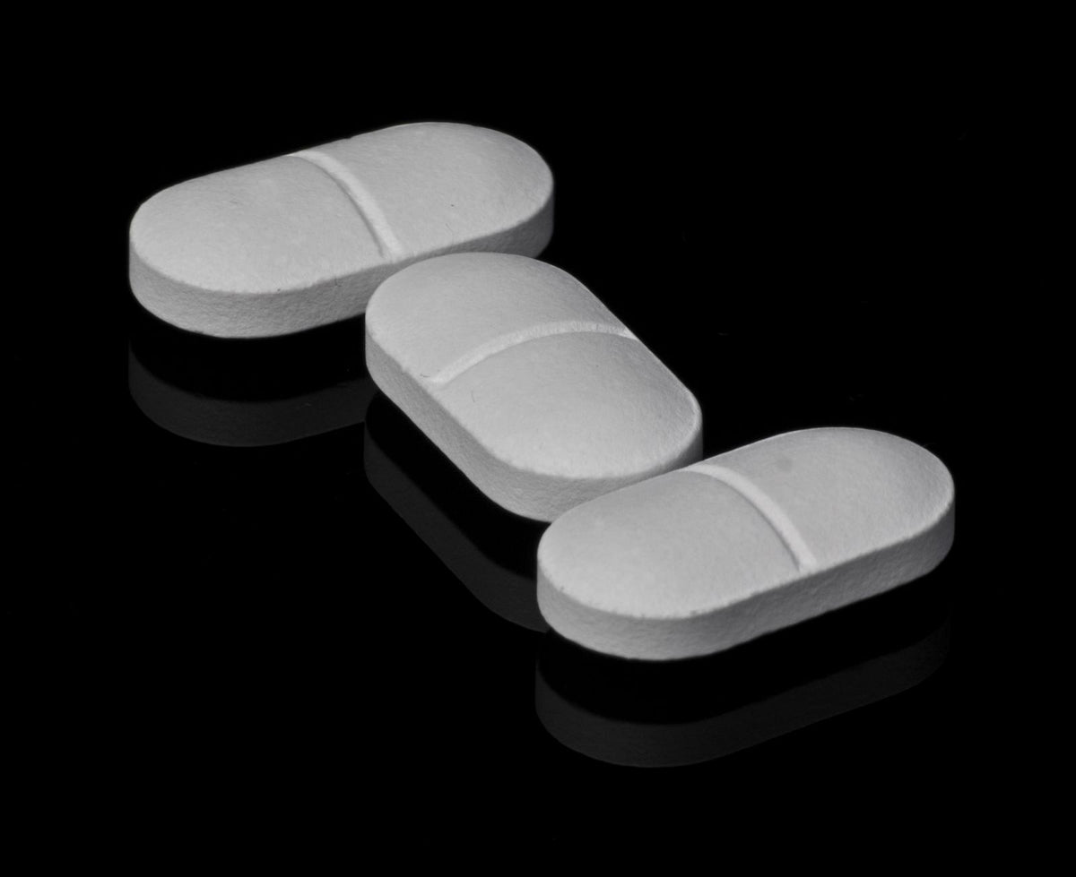 Three white tablets on a dark surface