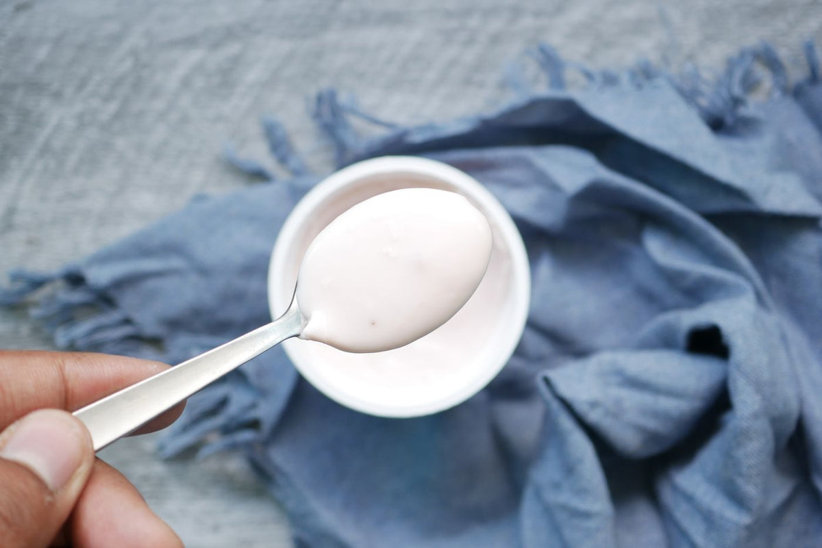 A spoonful of curd held over a bowl