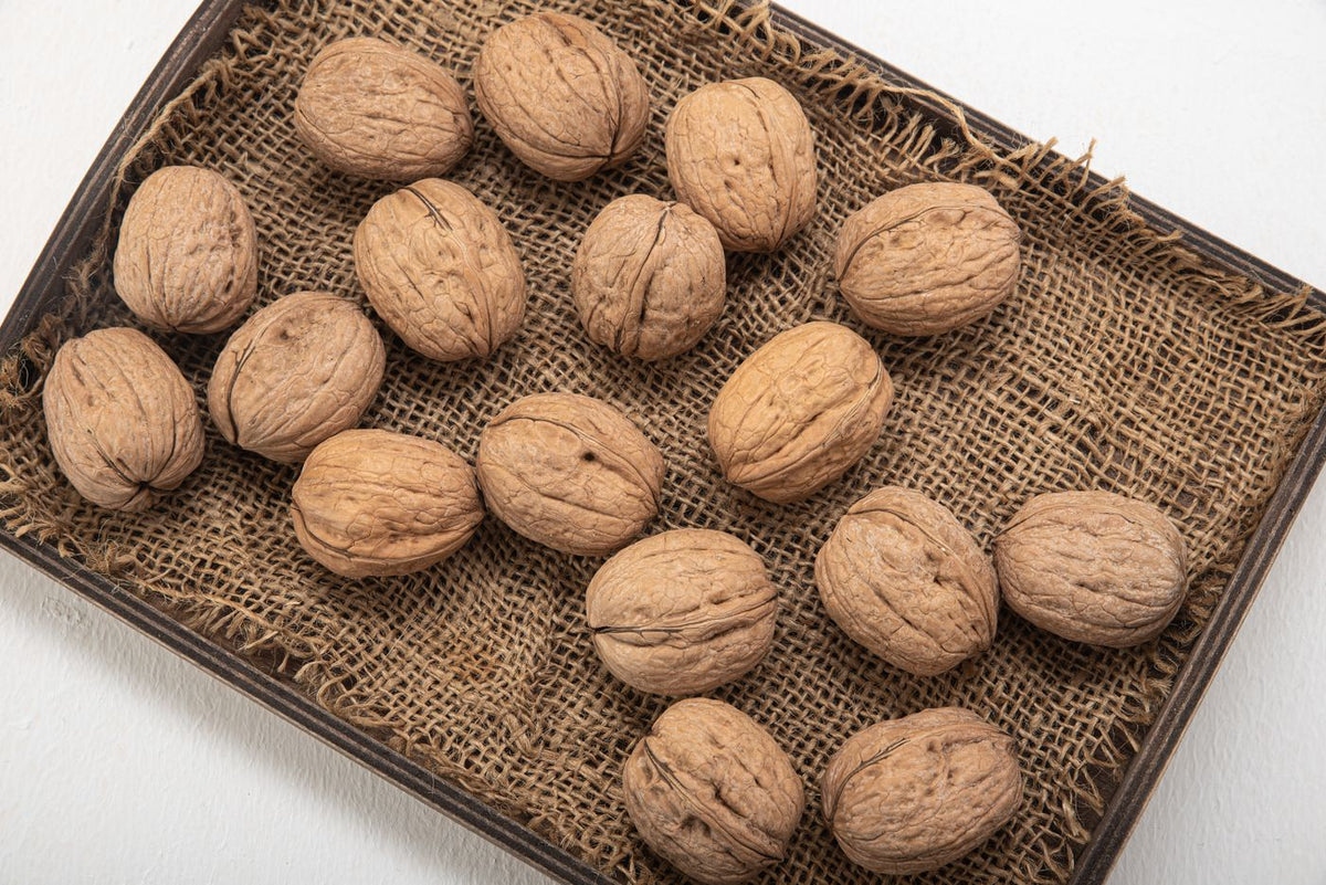 Whole walnuts in their shells on a burlap-lined tray