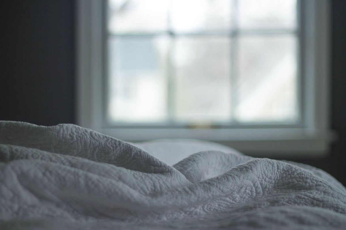 A bed by the window in soft morning light