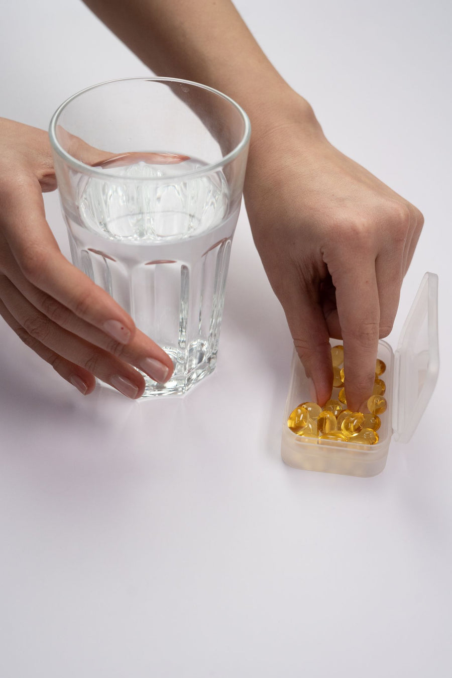 Taking a supplement from a pill organiser with a glass of water