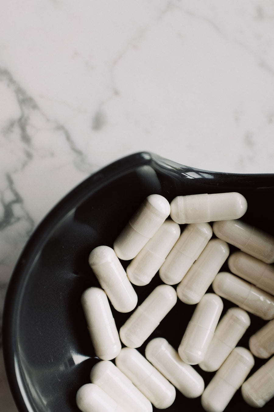 White capsules in a black bowl